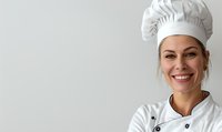 Smiling young Caucasian female chef in white uniform and traditional toque blanche hat against light background, professional culinary portrait with copy space.