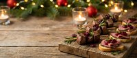 Festive holiday appetizers with cranberries and herbs on wooden board, Christmas party food spread with warm bokeh lights and seasonal decorations.