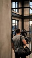 Athletic Caucasian man with gym bag entering modern fitness center through glass doors for workout session.