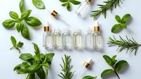 Natural essential oil bottles with fresh herbs basil rosemary mint on white background for aromatherapy wellness spa skincare organic cosmetics.