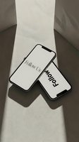 Two modern smartphones displaying Follow Us text arranged on a neutral beige surface with soft dramatic shadows for social media branding.