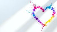Colorful paint splashes forming heart shape on white background with copy space for romantic designs and creative projects.