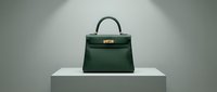 Green leather handbag with gold hardware displayed on white pedestal against neutral background, suitable for luxury fashion, retail, and e-commerce design projects.