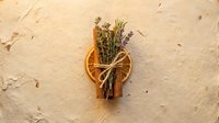 Dried orange slice, cinnamon sticks, lavender, and rosemary tied with twine on rustic paper background, natural aromatherapy composition.