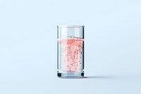 Glass of sparkling pink water with bubbles on light blue background, minimalist composition for healthy lifestyle and refreshment concepts.