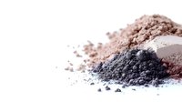 Colorful cosmetic powder makeup eyeshadows in neutral tones scattered on white background for beauty and fashion applications.
