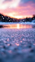 Magical winter sunset over frozen lake with sparkling snow crystals and bokeh light effects reflecting pink and purple sky colors in peaceful nature scene.