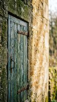 Weathered blue wooden door with peeling paint on ancient stone wall creates rustic charm for renovation and restoration projects.