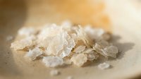 Sea salt crystals scattered on neutral surface with warm golden lighting and soft focus background.