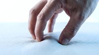 Male hands with fingers forming heart shape on light blue textured surface, expressing love, care, and compassion for relationships, charity, and wellness concepts.