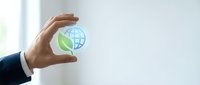 Businessman hand holding glowing globe with green leaf icon, symbolizing sustainable business, eco-friendly corporate responsibility and environmental awareness.