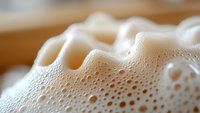 Macro shot of white creamy foam with bubbles and soft texture showing delicate details and patterns, suitable for beverage and coffee industry backgrounds.