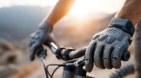 Mountain biker hands in protective gloves gripping handlebars during sunrise ride through scenic terrain for outdoor adventure sports and cycling.