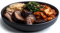 Grilled beef steak slices with rice, sautéed spinach and roasted vegetables in black bowl. Restaurant quality meal for food blogs and menus.