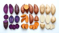 Assorted potato varieties including purple, red, and russet types shown whole and sliced on white background for culinary, agricultural, and food styling projects.