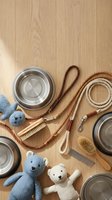 Pet care essentials flat lay with stainless steel bowls, rope leashes, grooming brushes, and stuffed toys arranged on natural wood background.