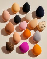 Colorful makeup beauty blender sponges in various shapes and textures casting soft shadows on beige background, flat lay composition for cosmetic and beauty industry.