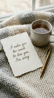Handwritten apology note on textured paper beside a warm tea mug and pen on a cozy knit blanket near a window.