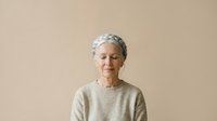 Senior woman with short gray hair wearing beige sweater against neutral background. Suitable for healthcare, wellness, aging, lifestyle and portrait projects.