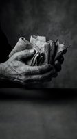 Elderly hands holding crumpled papers and fabric scraps in dramatic black and white lighting for artistic and conceptual projects.