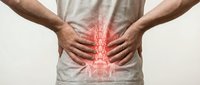 Man holding lower back with glowing red spine overlay highlighting lumbar pain, sacrum and pelvis anatomy for medical and healthcare use.