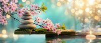 Zen spa composition with balanced stones, cherry blossoms, candles and water reflection creating peaceful meditation atmosphere for wellness and relaxation.