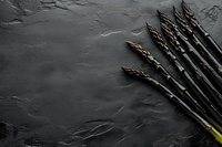 Fresh raw black asparagus spears arranged on dark stone background with copy space, dramatic moody food photography for restaurant menu design.