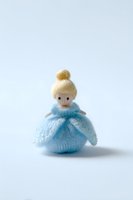 Handmade knitted doll in blue dress with blonde hair bun isolated on white background for crafts and toy design projects.
