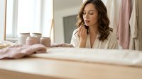 Young woman in white robe relaxing in bright bathroom with natural light, peaceful morning routine, self-care and wellness lifestyle concept.