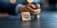 Wooden cube with happy smiley face drawn on it against blurred background, representing positive attitude, happiness and emotional wellbeing concept.