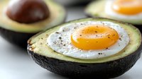 Baked egg in avocado half with pepper seasoning, healthy breakfast option for keto and low-carb diets.