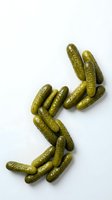 Dill pickles arranged in arrow shape on white background, isolated for food packaging, recipe blogs, and culinary design projects.