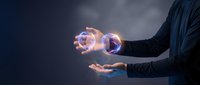Young adult male professional in dark business attire holding glowing purple energy orbs in open palms against dark background, representing innovation, technology, power, and future concepts for corporate and business applications.