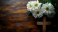 White chrysanthemum flowers and wooden cross on dark rustic wooden background with dramatic lighting, spiritual and memorial concept for sympathy card design.