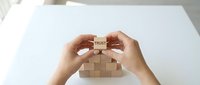 Hands placing wooden block with trust text on pyramid structure symbolizing business foundation and reliability concepts for corporate strategy.
