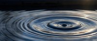 Water ripples creating concentric circles on calm surface with golden light reflections. Natural fluid motion pattern for meditation and wellness concepts.
