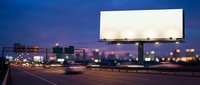 Blank white billboard on highway at dusk with city lights and traffic, suitable for advertising mockups and outdoor marketing campaigns.