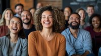 Diverse group of young professionals laughing together during casual meeting or team building event. Natural expressions capture workplace joy and inclusivity.