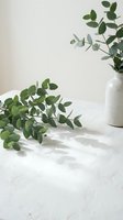 Fresh eucalyptus branches arranged on white marble surface with ceramic vase, ideal for home decor, wellness, and lifestyle design projects.
