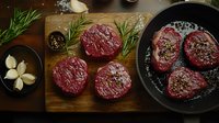 Raw beef tenderloin steaks seasoned with rosemary and garlic on wooden cutting board and cast iron pan, dark moody food photography styling.