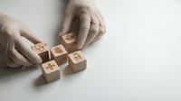 Hands arranging wooden blocks with social media icons on white surface for digital marketing strategy and communication concepts.