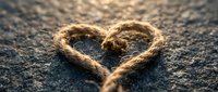 Heart-shaped rope on textured surface symbolizing love, connection and unity. Rustic nautical design element for romantic and maritime themed projects.