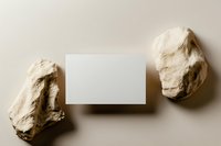 Blank white card mockup between two natural stones on beige background, flat lay composition for branding and stationery design.