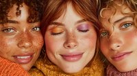 Three diverse young women with freckles and natural makeup lying together, showcasing friendship and beauty diversity for lifestyle campaigns.