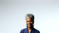 Senior African American woman with short gray hair wearing a navy blue button-up shirt, smiling at camera against white background for portrait and professional use.