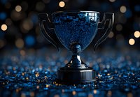 Dramatic trophy silhouette against dark background with blue glitter bokeh effects creating magical atmosphere for sports victory and achievement concepts.