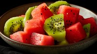 Fresh watermelon and kiwi fruit chunks in ceramic bowl on dark background, healthy summer fruit salad with vibrant colors and juicy texture.