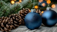 Navy blue matte Christmas ornaments with pine cones and fir branches against blurred warm lights background create festive holiday atmosphere.