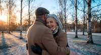 Senior couple embracing in snowy winter park at sunset, mature man and woman sharing romantic moment outdoors during golden hour, love and togetherness concept.