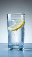 Glass of sparkling water with fresh lemon slice and ice cubes, refreshing beverage for summer drinks, hydration and wellness concepts.